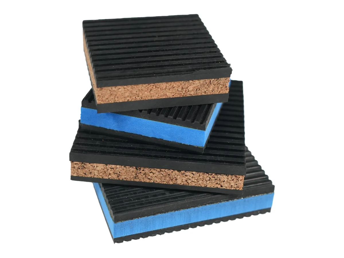 Cork core and blue EVA core anti vibration pads stacked, showing the ribbed rubber facings on both sides
