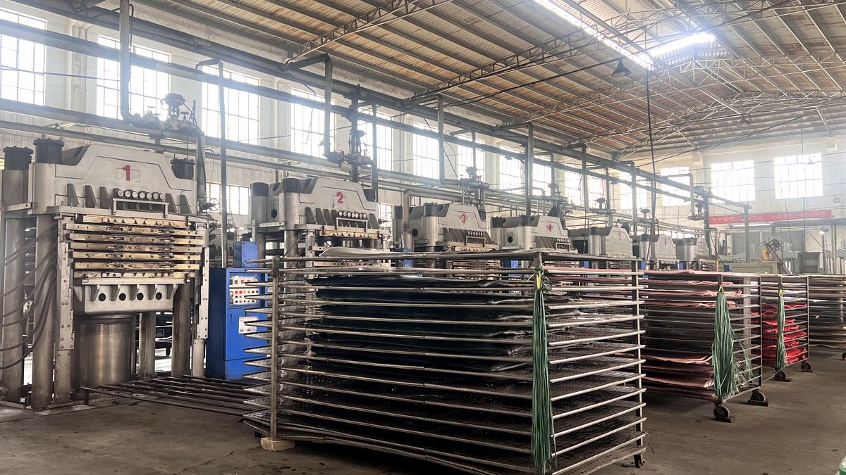 Row of numbered hydraulic presses and racks of rubber sheet at the SANSD foam factory in Jinjiang, Fujian, China