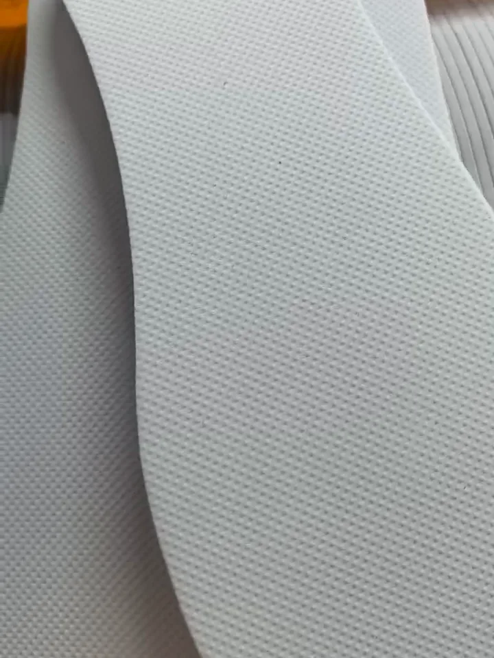 Stack of white die-cut EVA foam soles for disposable hotel slippers with a fine textured face